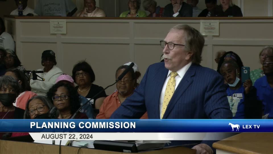 Simpson at the Planning Commission podium with St. Martin's Village residents seated in the audience behind him