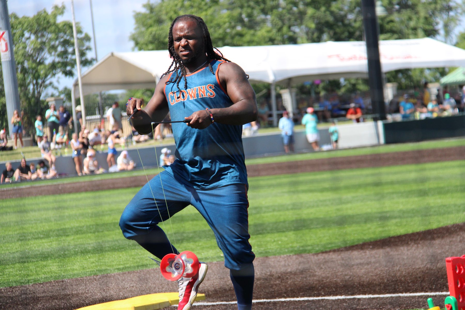 A Clowns player works a diabolo on the first-base line between innings.