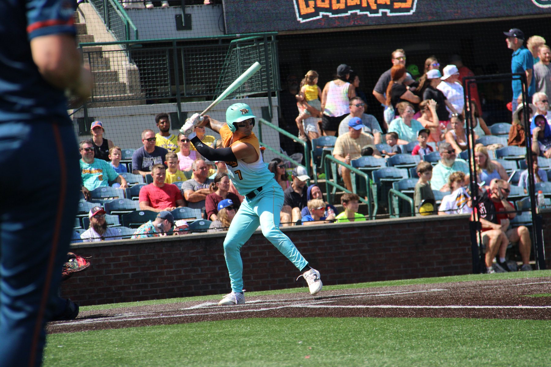 A Coconuts hitter swings in front of a packed first-base side.