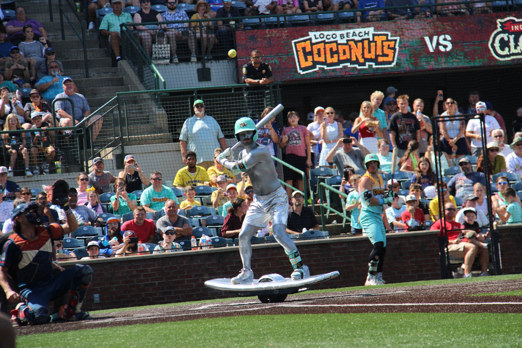 A Loco Beach Coconuts hitter in full silver body paint bats from a balance board.